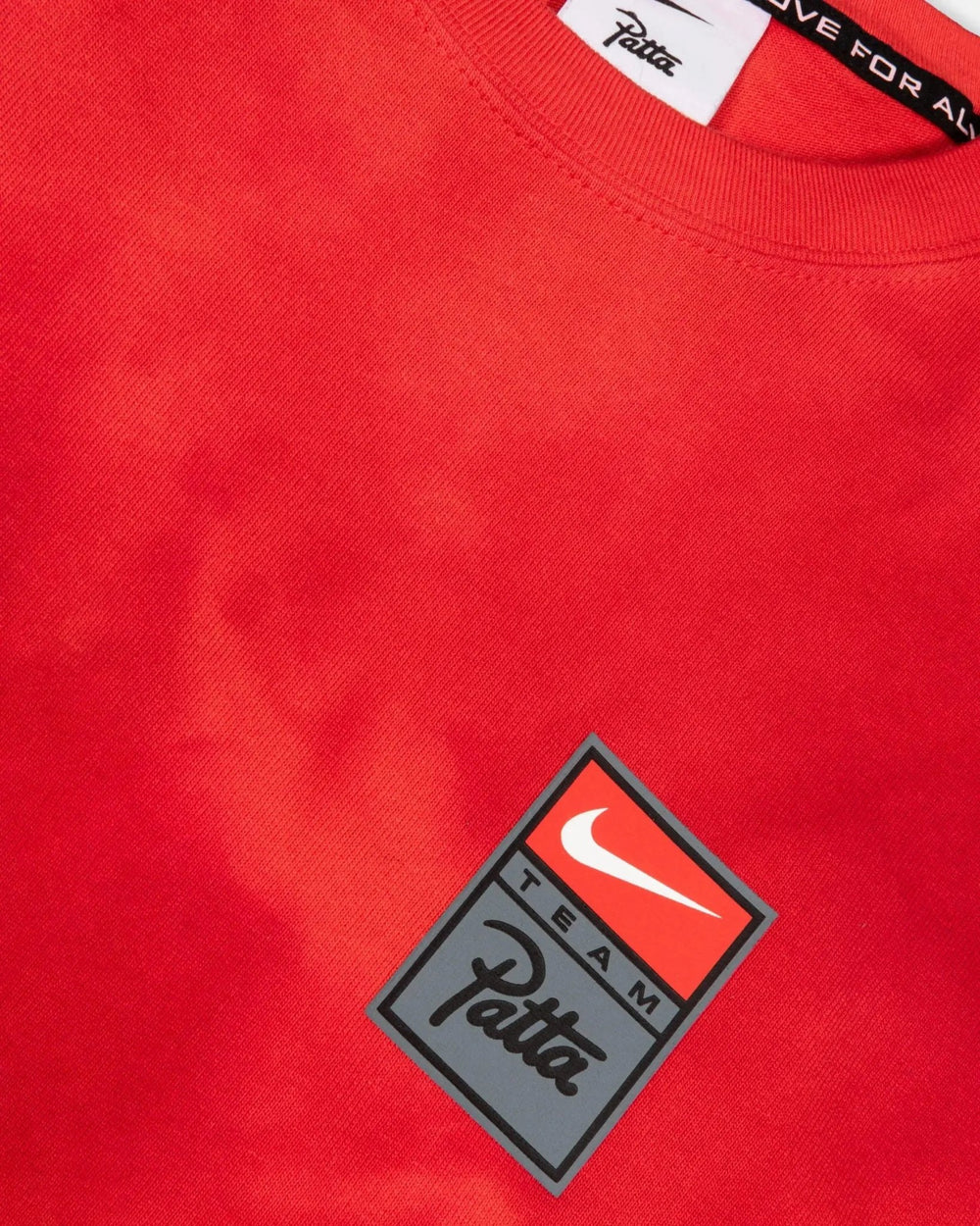 Detail of the washed red Patta x Nike NRG T-shirt featuring the silicone Team Patta chest badge.